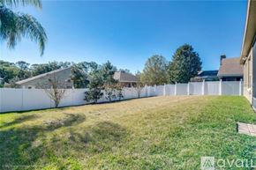 Apopka apartment for rent - A white fence separates a grassy area from a building.