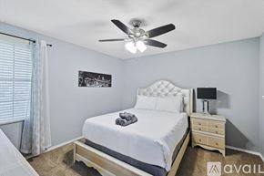 Grand Prairie house for rent - A bedroom with a large bed, a ceiling fan, and a nightstand with a lamp.