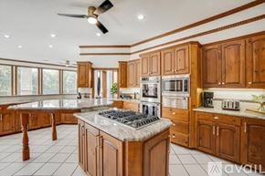 Garland house for rent - A kitchen with wooden cabinets and a marble countertop.