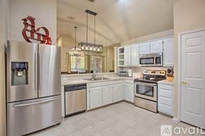 Rowlett house for rent - A kitchen with white cabinets and a stainless steel refrigerator.