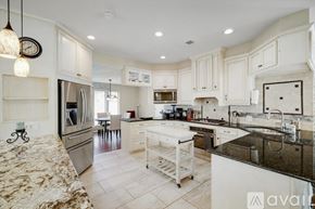 Lewisville house for rent - A kitchen with white cabinets and a black fridge.