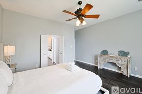 Rowlett house for rent - A bedroom with a white bed and a ceiling fan.