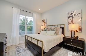 Houston house for rent - A bedroom with a large bed and a window with white curtains.