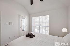 Plano house for rent - A bedroom with a large bed and a window with blinds.