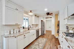 Keller house for rent - A kitchen with white cabinets and a wooden floor.