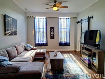 Chicago apartment for rent - A living room with a brown couch and a ceiling fan.