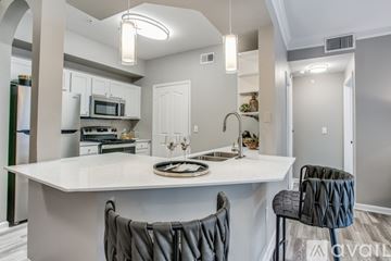 Lewisville apartment for rent - A modern kitchen with a white island and grey chairs.