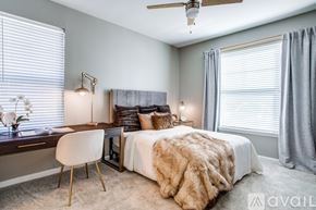 Lewisville apartment for rent - A bedroom with a large bed, a desk with a chair, and a ceiling fan.