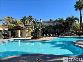 Huntington Beach townhouse for rent - A pool surrounded by palm trees and lounge chairs.