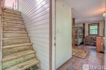Rabun Gap house for rent - A wooden staircase leads to a living room with a couch and a rug.