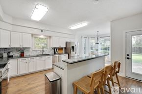 Flower Mound house for rent - A kitchen with white cabinets and a black counter top.