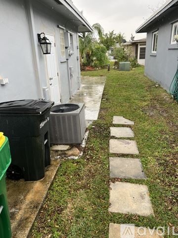 Margate house for rent - A wet walkway leads to a house with a green trash can on the left.