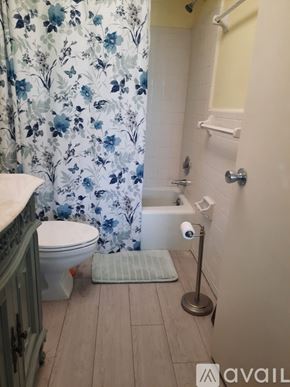 St. Pete Beach apartment for rent - A bathroom with a floral shower curtain and a white toilet.