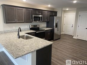 New Hartford apartment for rent - A kitchen with dark brown cabinets and a granite countertop.