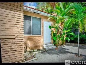 Miami Beach apartment for rent - A house with a blue door and a window is surrounded by greenery.