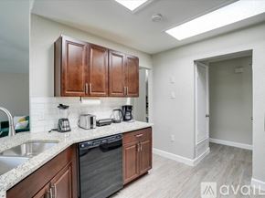 Lewisville house for rent - A kitchen with wooden cabinets and a black dishwasher.