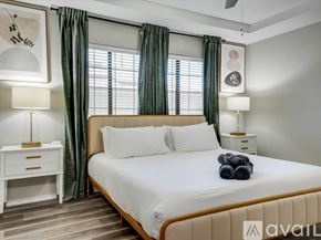 Lewisville house for rent - A bedroom with a large bed, a nightstand with a lamp, and a wall-mounted fan.