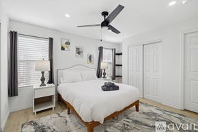 Dallas house for rent - A bedroom with a white bed, a ceiling fan, and a rug on the floor.