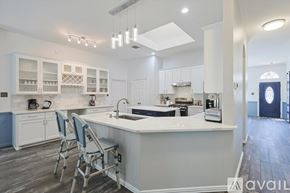 Corinth house for rent - A kitchen with white cabinets and a large island with chairs.