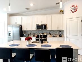 Ave Maria condo for rent - A kitchen with white cabinets and a large island with a sink and a refrigerator.