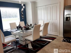 Ave Maria condo for rent - A modern dining room with white chairs and a glass table.