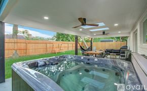 Friendswood house for rent - A hot tub is in the middle of a patio with a ceiling fan and a deck.