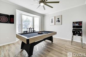 Lewisville house for rent - A pool table in a room with a ceiling fan and a dartboard on the wall.