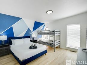 Denton house for rent - A bedroom with a large bed and bunk beds in the background.