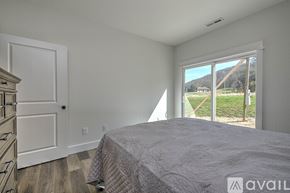 Johnson City apartment for rent - A bedroom with a large bed and a view of the outside through a sliding glass door.