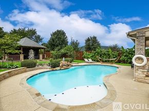 Kennedale house for rent - A swimming pool surrounded by a stone wall and a gazebo.