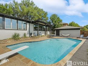 Rockwall house for rent - A pool in a backyard with a house and trees in the background.