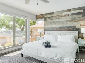 Rockwall house for rent - A bedroom with a white bed and a wooden wall.