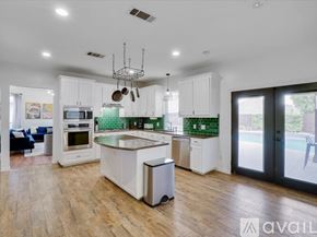 Haltom City house for rent - A modern kitchen with white cabinets and a wooden floor.