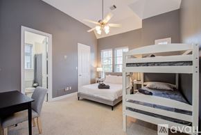 Houston house for rent - A bedroom with a white bunk bed and a single bed with a ceiling fan.