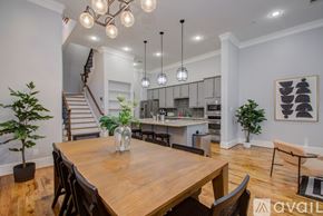 Houston house for rent - A dining room with a wooden table and chairs, a staircase, and a kitchen area in the background.