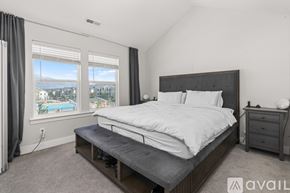Lehi apartment for rent - A bedroom with a large bed, a nightstand, and a window overlooking a pool.