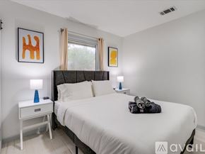 Irving house for rent - A bedroom with a large bed, a nightstand with a blue lamp, and two wall art pieces.
