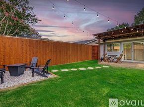 Irving house for rent - A backyard with a wooden fence, a hot tub, and a patio area.
