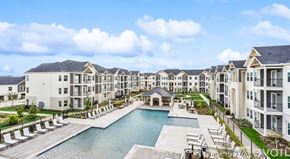 New Braunfels apartment for rent - A large, modern apartment complex with a pool in the foreground.