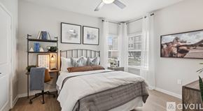 New Braunfels apartment for rent - A bedroom with a bed, a chair, a shelf with books and a plant, and a painting on the wall.