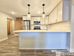 Chicago apartment for rent - A spacious room with wooden flooring and white walls, with a logo for BEAL PROPERTIES in the corner.