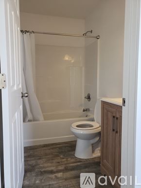 Green Forest apartment for rent - A white toilet in a bathroom with a wooden cabinet.
