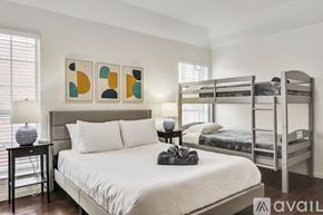 Plano house for rent - A bedroom with a white bed, a grey headboard, and a bunk bed in the background.
