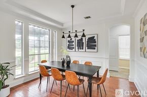 Plano house for rent - A dining room with a black table and orange chairs.