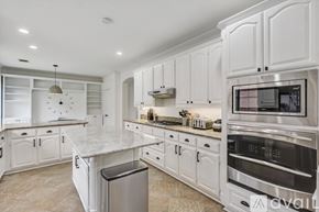 Plano house for rent - A modern kitchen with white cabinets and a marble countertop.