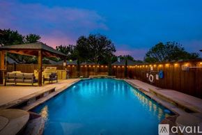 Lewisville house for rent - A pool with a wooden deck and a gazebo with lights around it.
