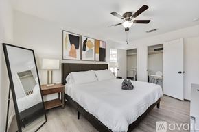 Fort Worth house for rent - A bedroom with a large bed, a ceiling fan, and a painting on the wall.