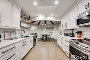 Plano house for rent - A modern kitchen with white cabinets and a wooden floor.