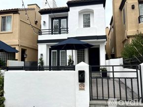 Huntington Beach house for rent - A white house with black railings and a black umbrella.