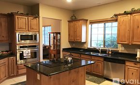 Prescott house for rent - A kitchen with wooden cabinets and black countertops.